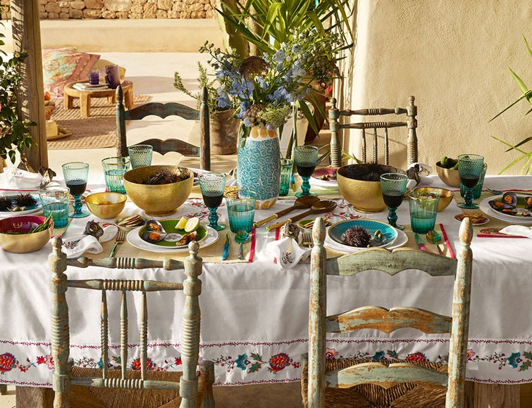 Comedor exterior con vajilla artesanal y cristalería turquesa
