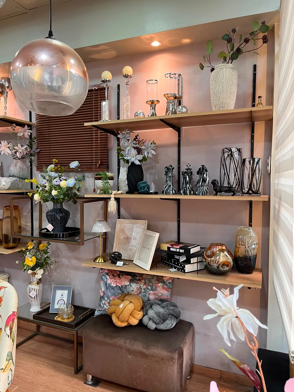 Estantes de decoración con jarrones, arreglos florales, marcos, libros y cojines de nudo en el bazar Ferrehome