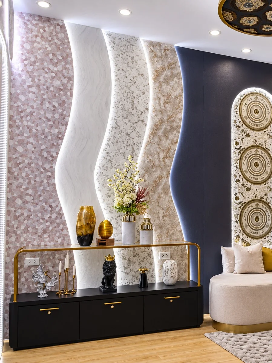 Paneles de papel mural ondulados e iluminados en rosa, blanco y dorado detrás de una consola negra con jarrones, en el stand Decopapel