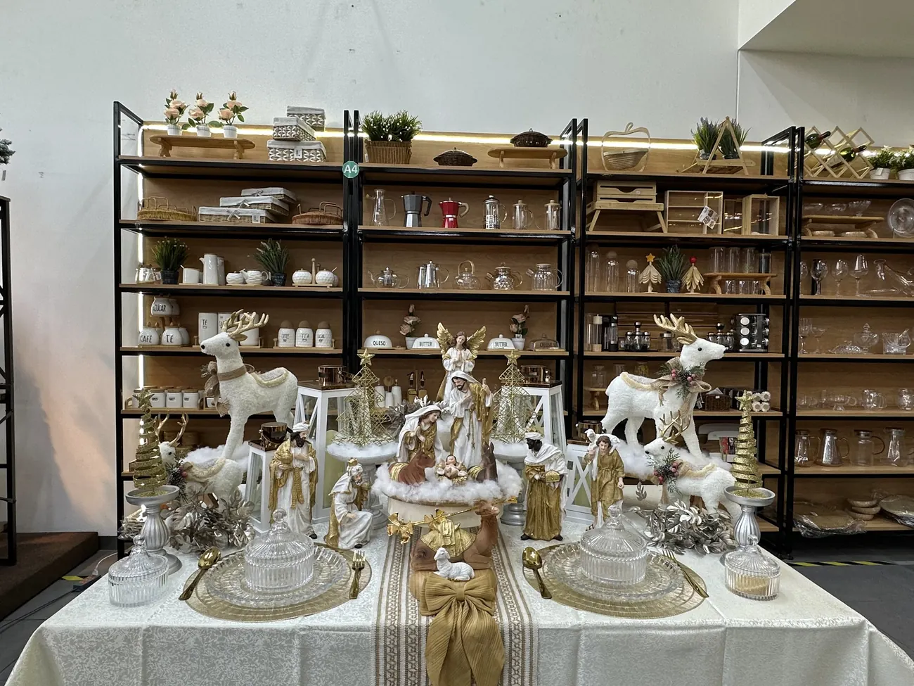 Mesa de nacimiento blanco y dorado sobre nieve de algodón, con renos blancos y árboles dorados, en SuperHome