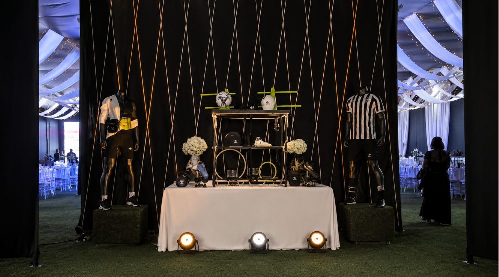 Arco de bienvenida con mannequins deportivos y mesa de producto en vitrina